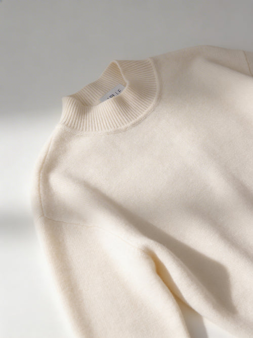 Ivoryfarbener Cashmere Pullover mit Halbrollkragen und langen Ärmeln, gefaltet