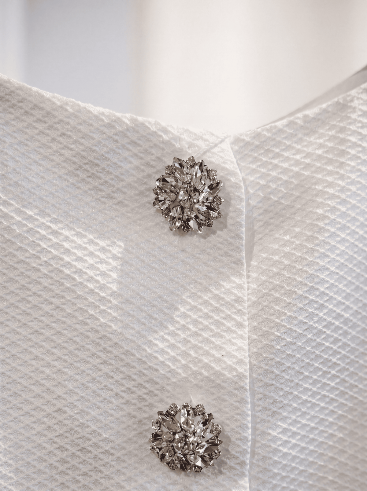 Detail der dekorativen Schmuckknöpfe am weißen Jacquardkleid