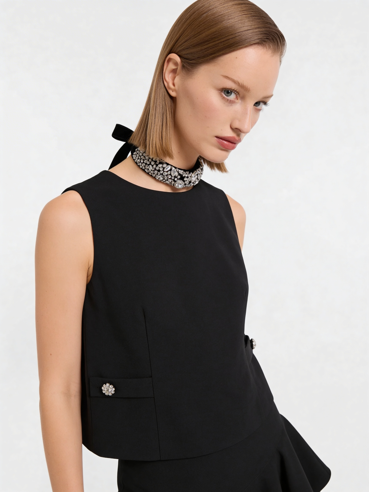 Model trägt schwarzes ärmelloses Wolltop mit eleganten Strassdetails