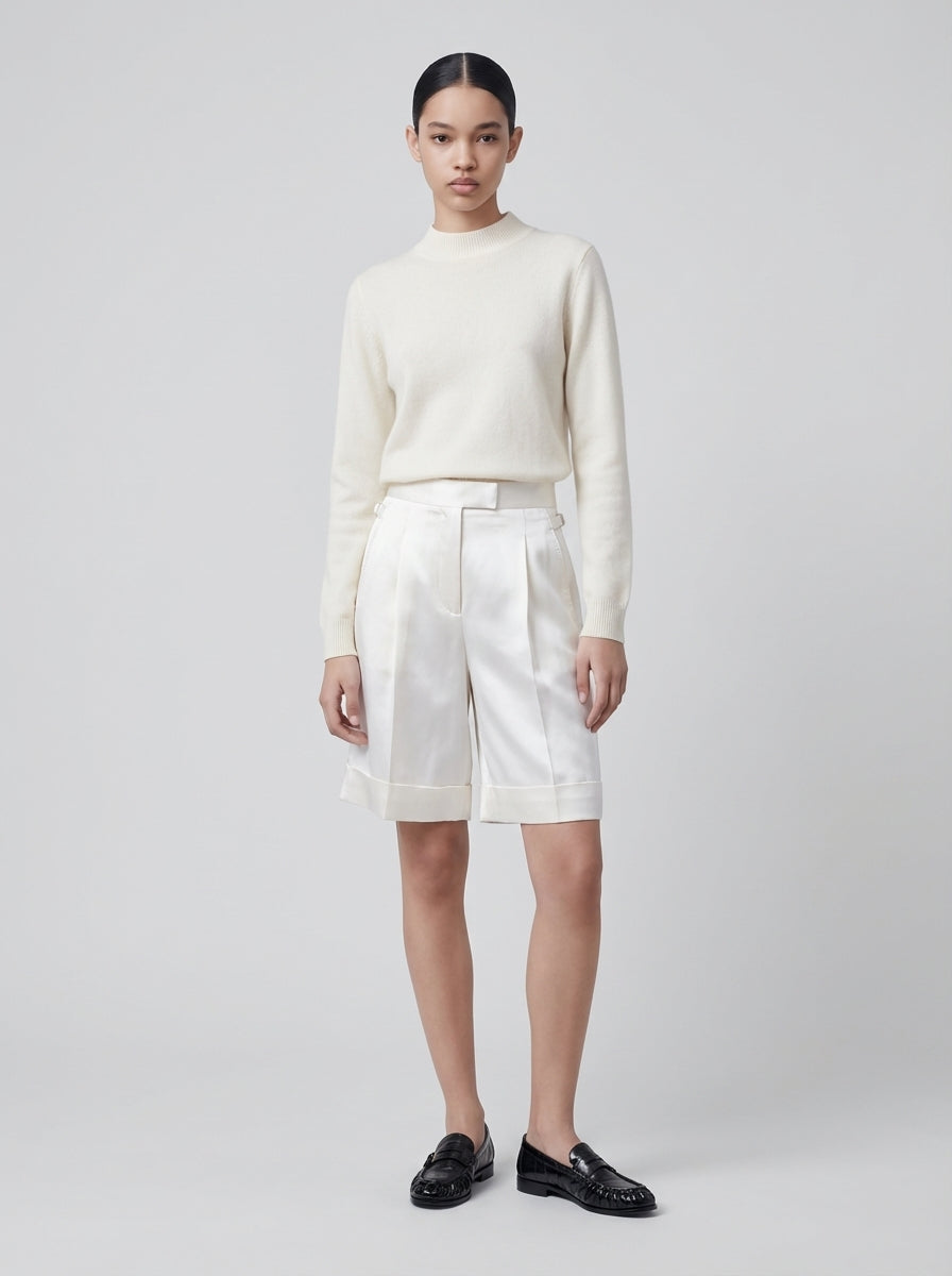 Model trägt ivoryfarbenen Cashmere Pullover mit Halbrollkragen und weißer Shorts
