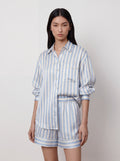 Model trägt lockere Seidenbluse im Oversize-Schnitt mit hellblau-weißen Streifen