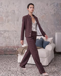 Model trägt karierten Wollblazer von AELLE COLLECTIVE mit passender Bundfaltenhose